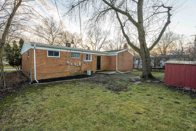 back of house featuring a storage shed, central AC, and a lawn