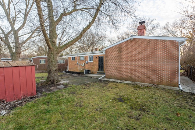 rear view of house featuring central AC, a lawn, and a shed