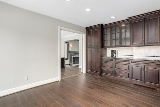 31265 Woodside Dr, Franklin, MI 48025 - bar with dark wood-style flooring, baseboards, recessed lighting, a fireplace with raised hearth, and tasteful backsplash
