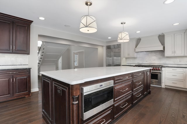 31265 Woodside Dr, Franklin, MI 48025 - kitchen featuring dark wood-style flooring, premium range hood, a center island, high end appliances, and tasteful backsplash