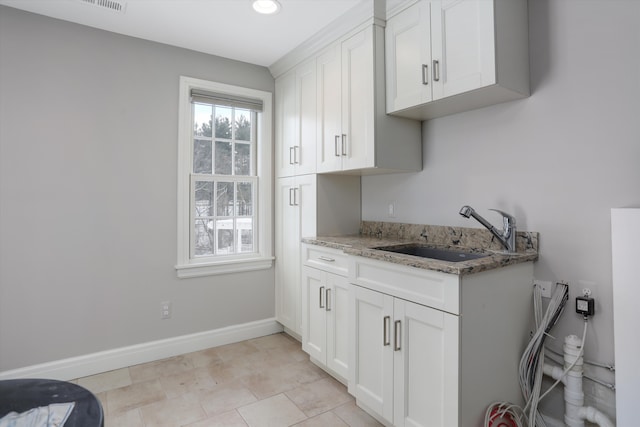 31265 Woodside Dr, Franklin, MI 48025 - interior space featuring light stone countertops, baseboards, white cabinetry, a sink, and light tile patterned floors