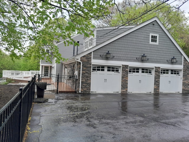 31265 Woodside Dr, Franklin, MI 48025 - view of side of property featuring an attached garage, aphalt driveway, fence, and stone siding