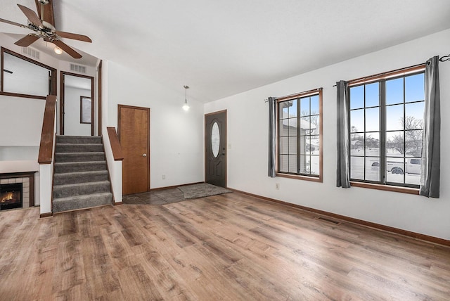 entryway with a tiled fireplace, wood-type flooring, lofted ceiling, and ceiling fan