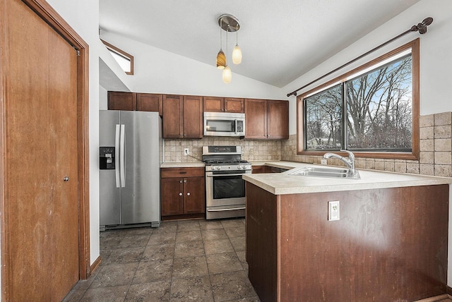 kitchen featuring sink, decorative light fixtures, vaulted ceiling, kitchen peninsula, and stainless steel appliances