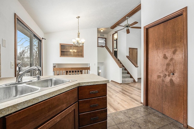 kitchen with sink, decorative light fixtures, lofted ceiling with beams, light hardwood / wood-style flooring, and ceiling fan with notable chandelier