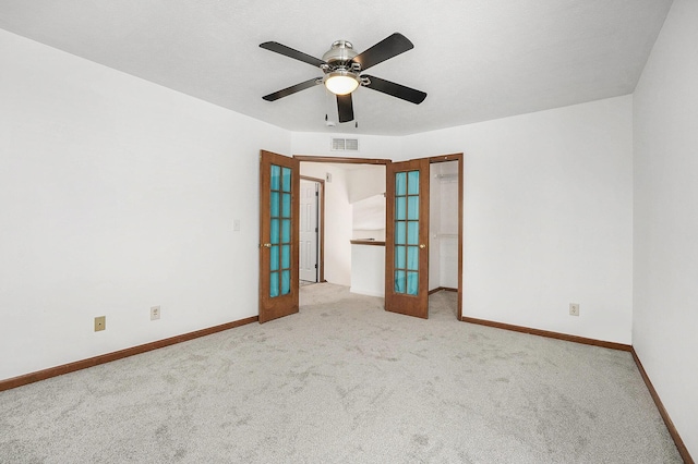 spare room with light carpet, french doors, and ceiling fan