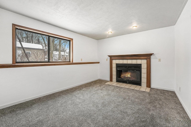 unfurnished living room featuring a tile fireplace, light colored carpet, and a textured ceiling