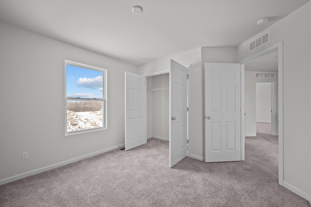 unfurnished bedroom with light colored carpet and a closet