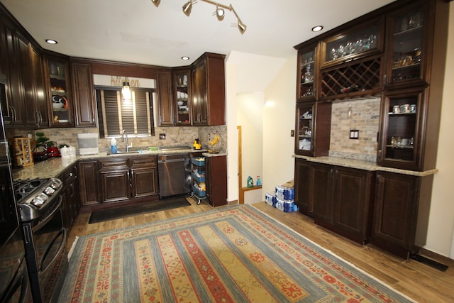 kitchen featuring sink, light stone counters, wood-type flooring, appliances with stainless steel finishes, and backsplash