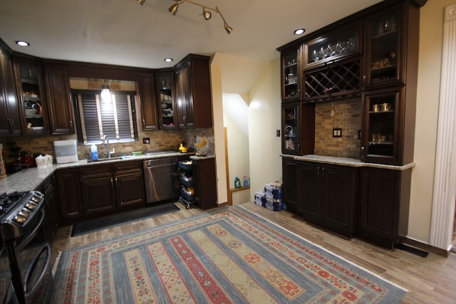 kitchen with sink, light hardwood / wood-style flooring, stainless steel dishwasher, black range with gas stovetop, and backsplash