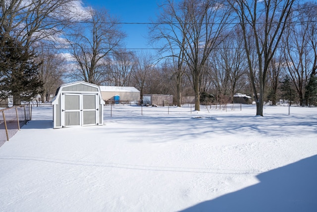 yard layered in snow featuring fence, an outdoor structure, and a shed