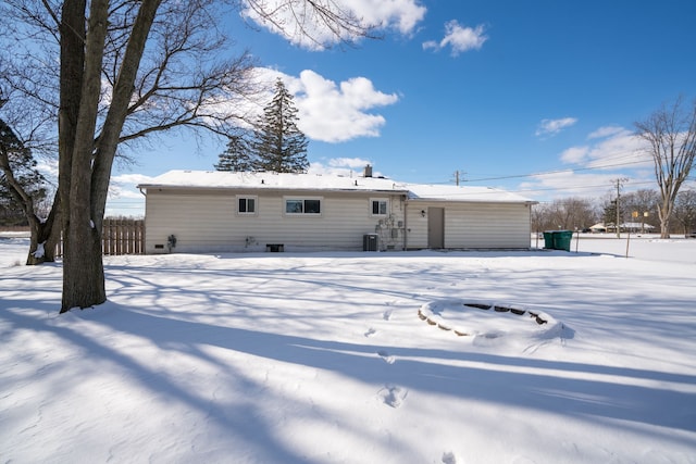 snow covered house with central AC and fence