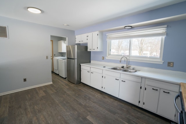 kitchen with freestanding refrigerator, a sink, light countertops, independent washer and dryer, and white cabinets