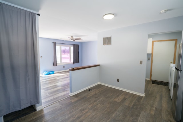 empty room with a ceiling fan, visible vents, baseboards, and dark wood-type flooring