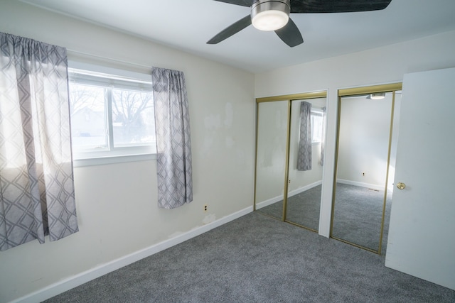 unfurnished bedroom with baseboards, a ceiling fan, multiple closets, and carpet