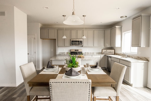 kitchen with appliances with stainless steel finishes, a center island, gray cabinets, and a sink