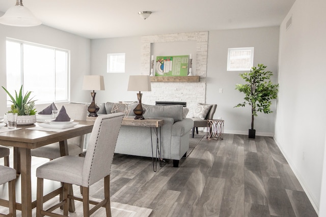 living room with baseboards, a fireplace, visible vents, and wood finished floors