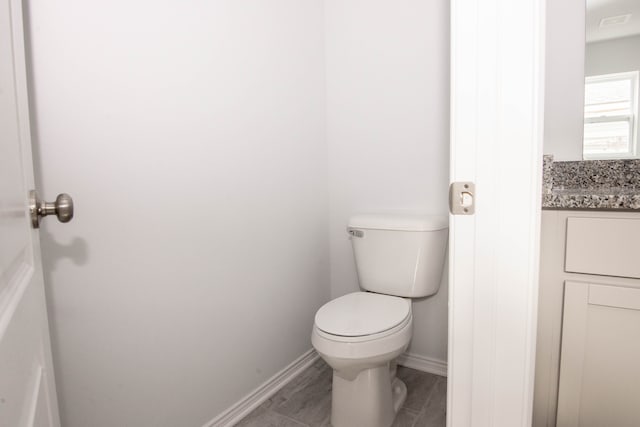 bathroom featuring baseboards, visible vents, toilet, and vanity