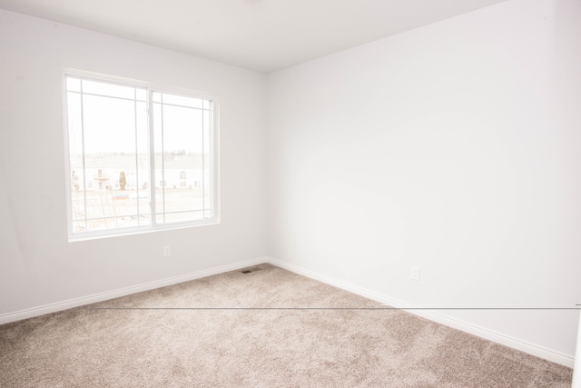 carpeted spare room with visible vents and baseboards