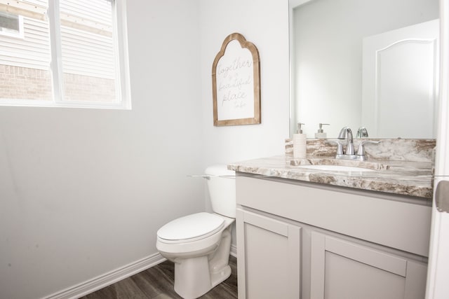 half bathroom featuring baseboards, vanity, toilet, and wood finished floors