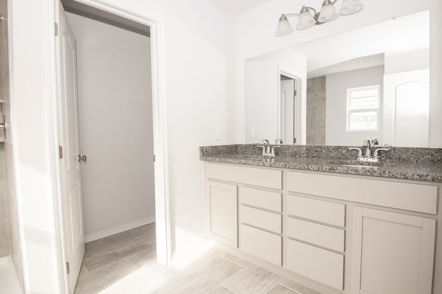 full bathroom with double vanity, baseboards, and a sink