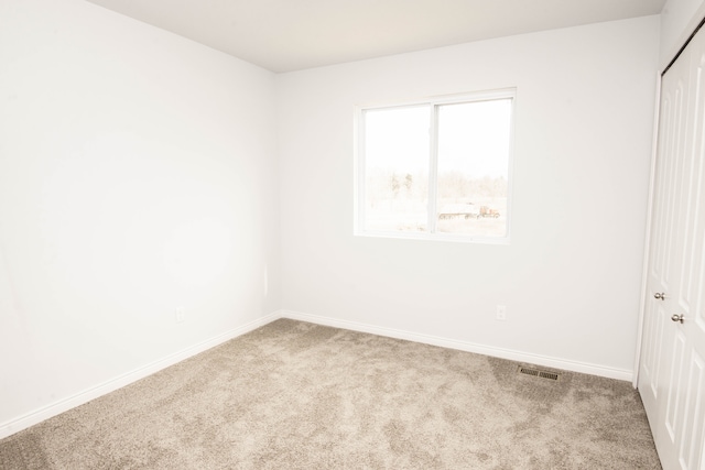 empty room with carpet floors, visible vents, and baseboards