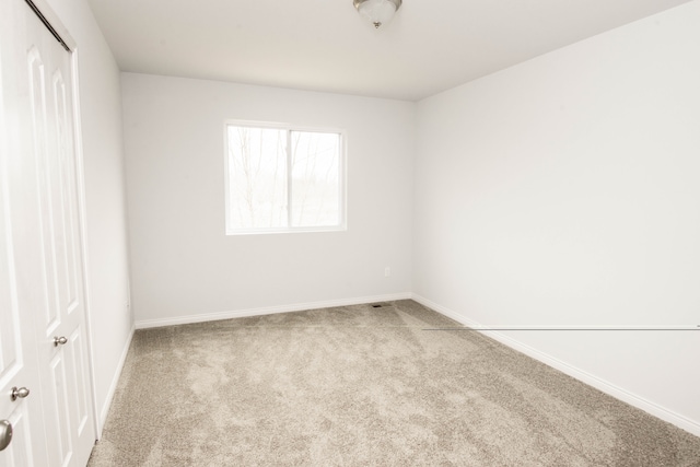 empty room featuring carpet and baseboards