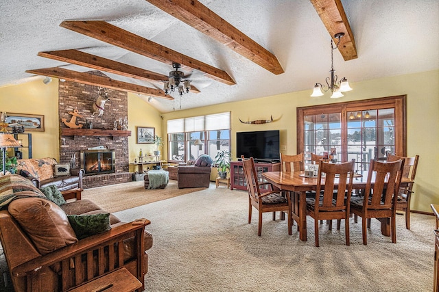 carpeted dining area with vaulted ceiling with beams, ceiling fan with notable chandelier, a fireplace, and a textured ceiling