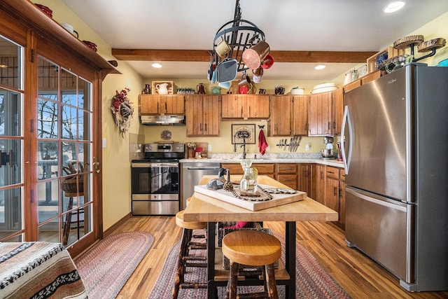 kitchen featuring appliances with stainless steel finishes, sink, beam ceiling, and light hardwood / wood-style flooring