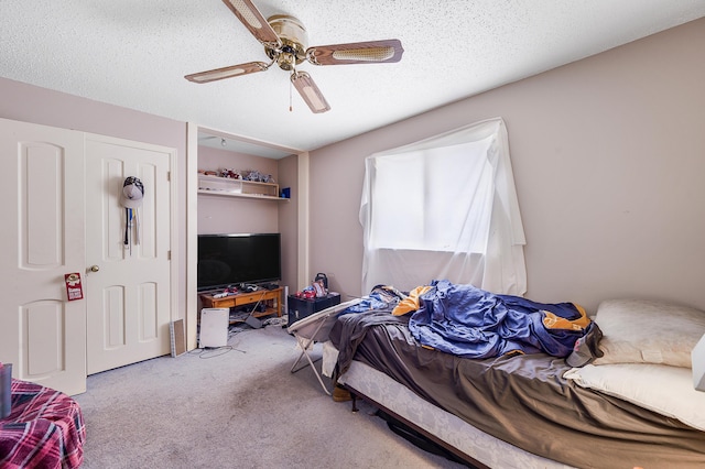 bedroom with a textured ceiling, light colored carpet, and ceiling fan