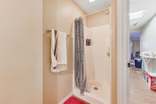 bathroom featuring hardwood / wood-style flooring, a paneled ceiling, and walk in shower