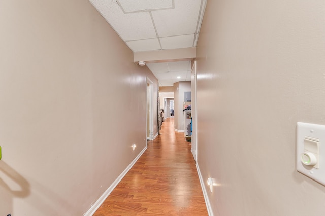 corridor with light hardwood / wood-style flooring and a paneled ceiling