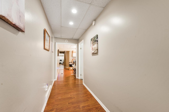 hall with wood-type flooring and a paneled ceiling