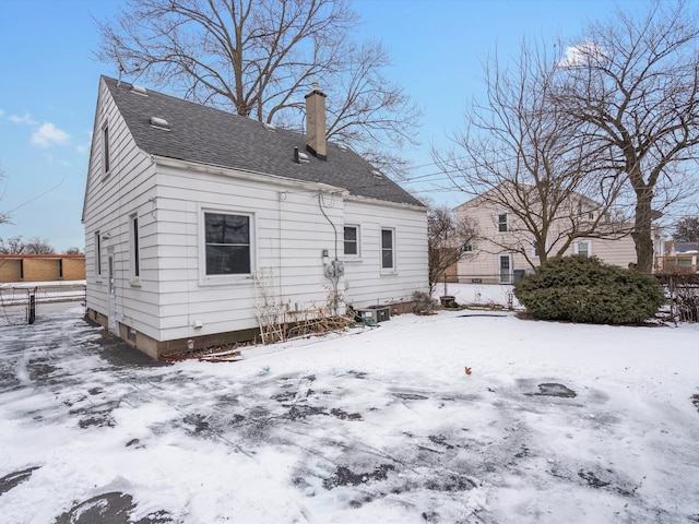 snow covered house featuring cooling unit