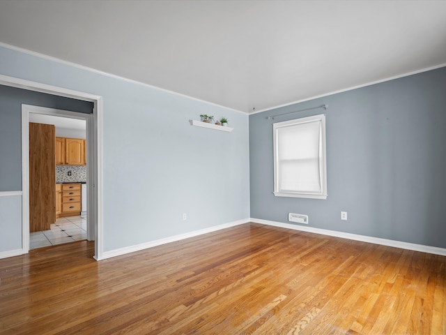 empty room featuring crown molding and light hardwood / wood-style flooring