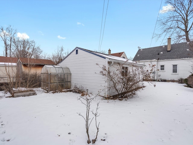 snow covered back of property with an outdoor structure