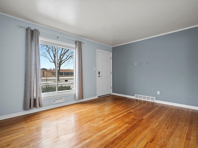 spare room featuring crown molding and light wood-type flooring