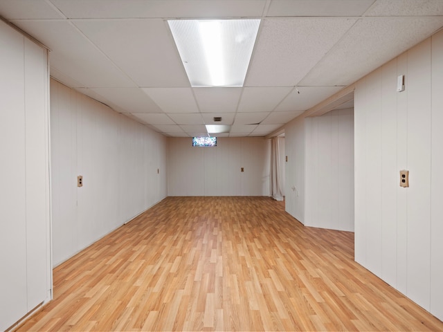 basement featuring a paneled ceiling and light wood-type flooring