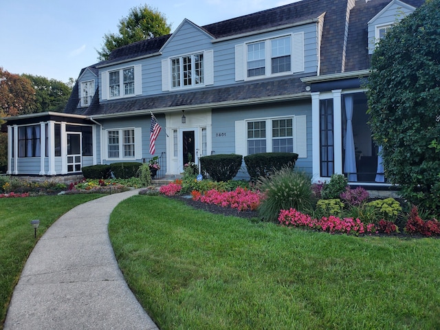 view of front of home with a front lawn and a sunroom