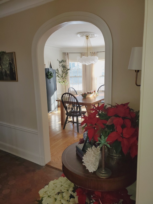 corridor with crown molding, wood-type flooring, and a notable chandelier