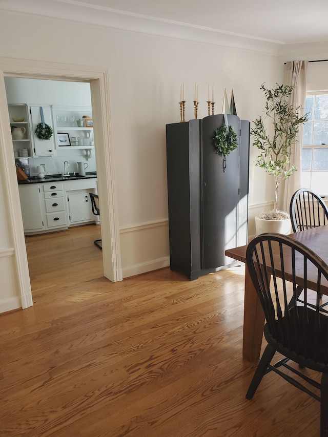 dining room with ornamental molding, sink, and light hardwood / wood-style flooring