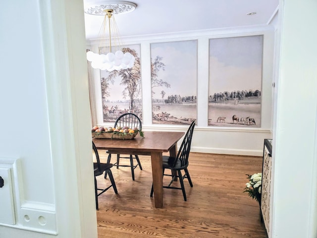 dining area with wood-type flooring, a notable chandelier, and crown molding