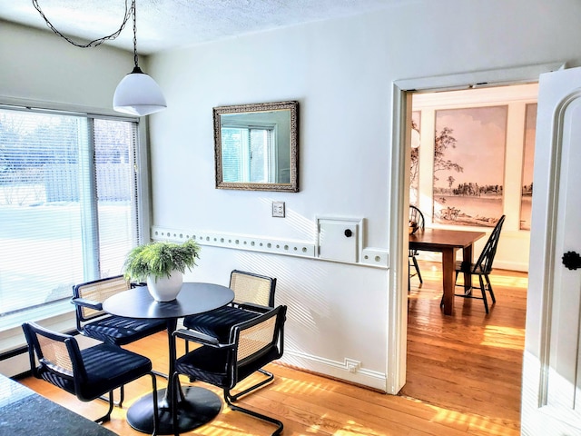 dining room with wood-type flooring and a textured ceiling