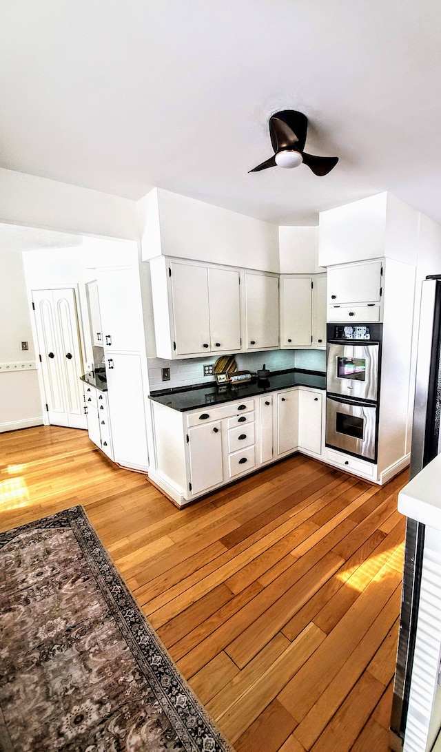 kitchen with white cabinetry, ceiling fan, appliances with stainless steel finishes, and light hardwood / wood-style floors