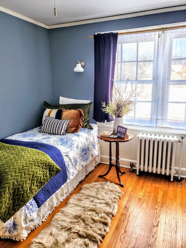 bedroom with crown molding, radiator heating unit, and hardwood / wood-style flooring