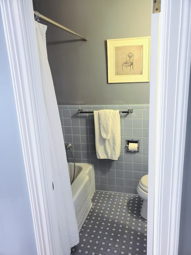 bathroom with tile walls, shower / bath combo, tile patterned floors, and toilet