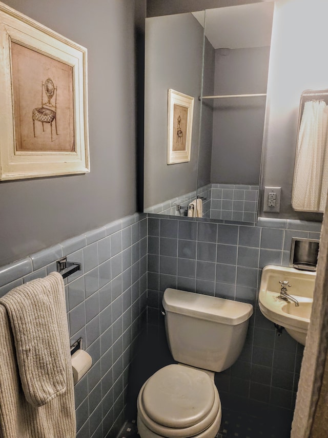 bathroom with sink, tile walls, and toilet