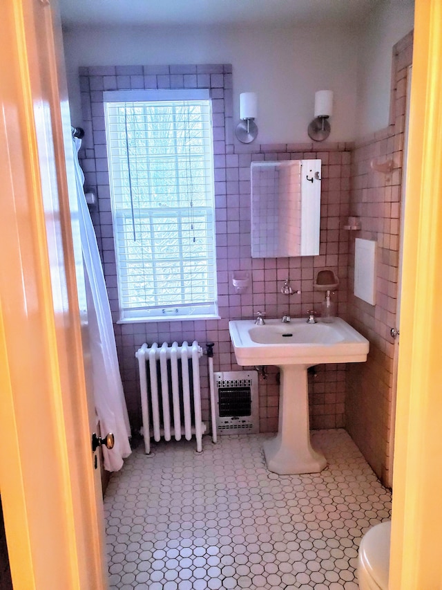 bathroom featuring heating unit, radiator, a wealth of natural light, and tile walls