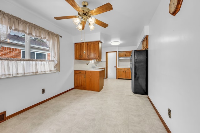 kitchen with sink, stainless steel fridge, ceiling fan, and kitchen peninsula