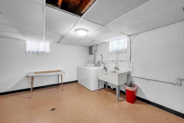 basement with a drop ceiling, washing machine and clothes dryer, and electric panel